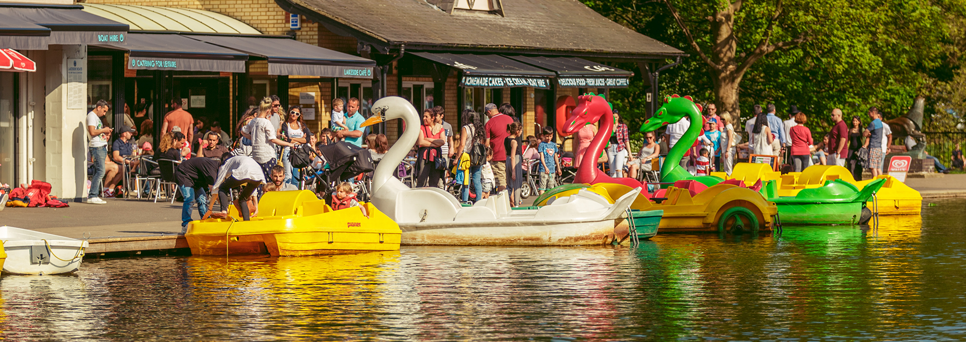 A crowd preparing to go out onto the lake on animal-shaped boats