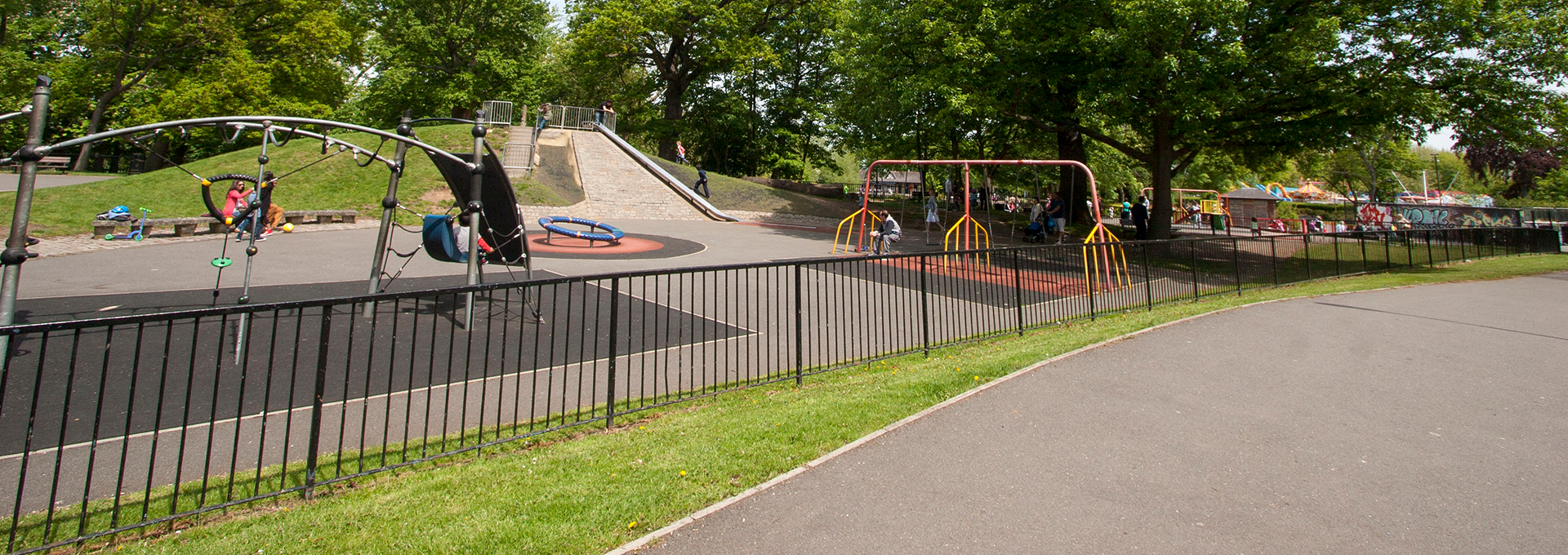 Empty children's playground looking towards a climbing frame and swings.