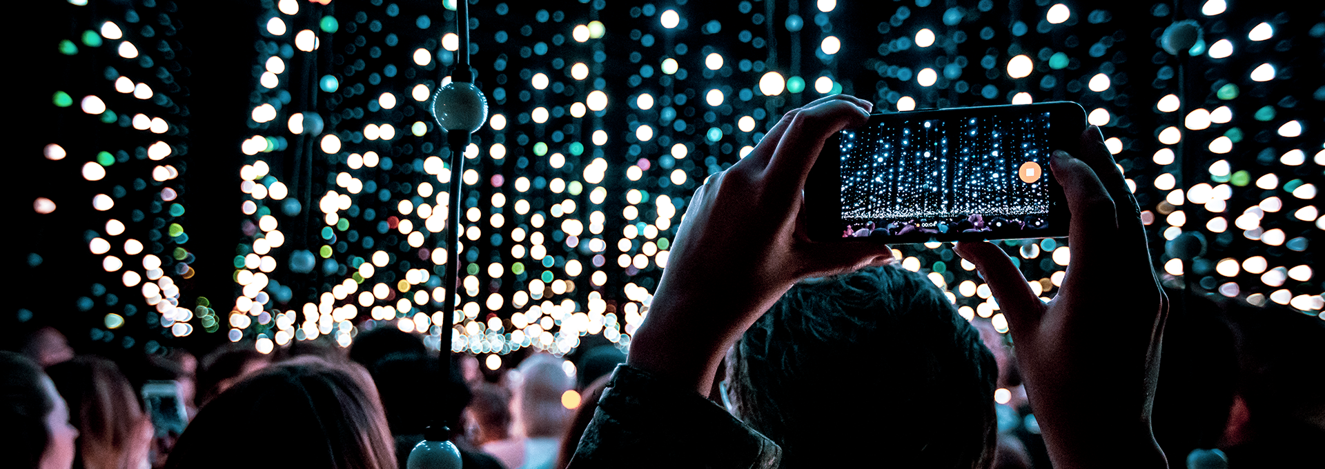 Crowd watching a light installation of lights suspended in darkness.