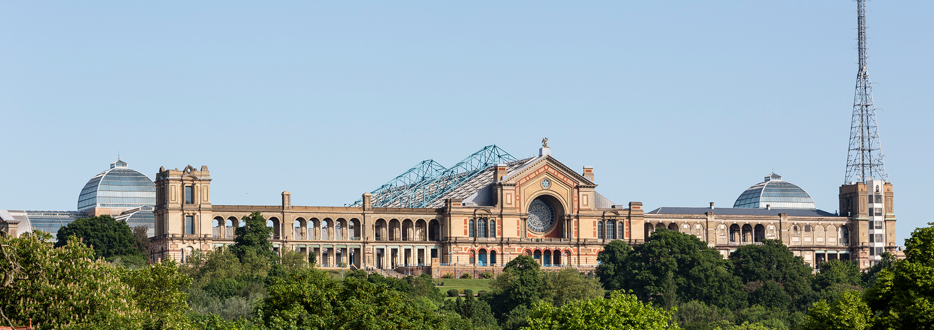 Frontal view of all of Alexandra Palace with a blue sky.