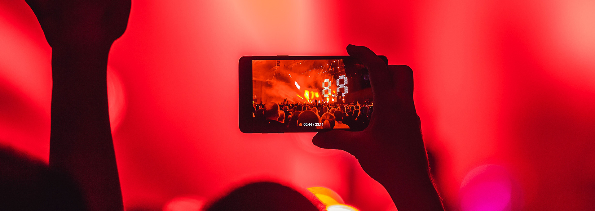 Someone in a crowd filming a concert on their phone