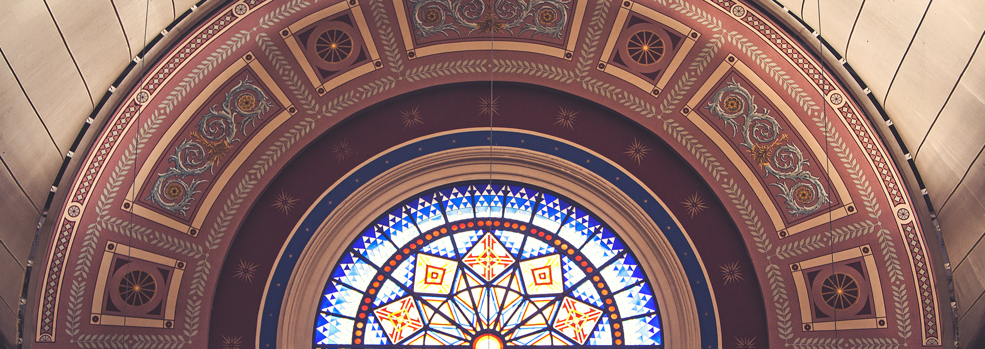 Rounded stained glass window with surrounded painted mural.