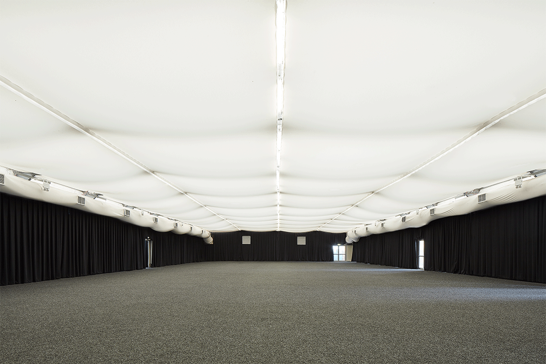 Large marquee at Alexandra Palace with black curtained walls and a white ceiling.