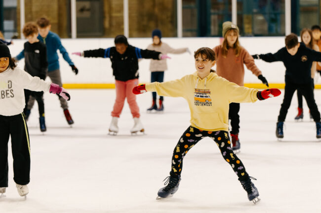 A child skating on an Ally pally Ice Rink, smiling.