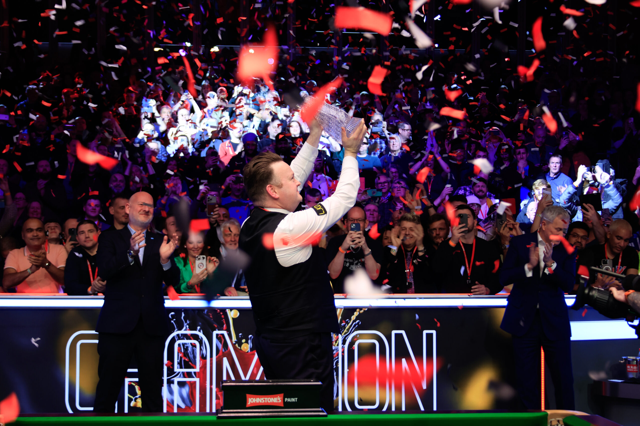 Shaun Murphy celebrates his win at the Snooker Masters 2025. He holds a glass trophy in the air shaped like a snooker triangle.